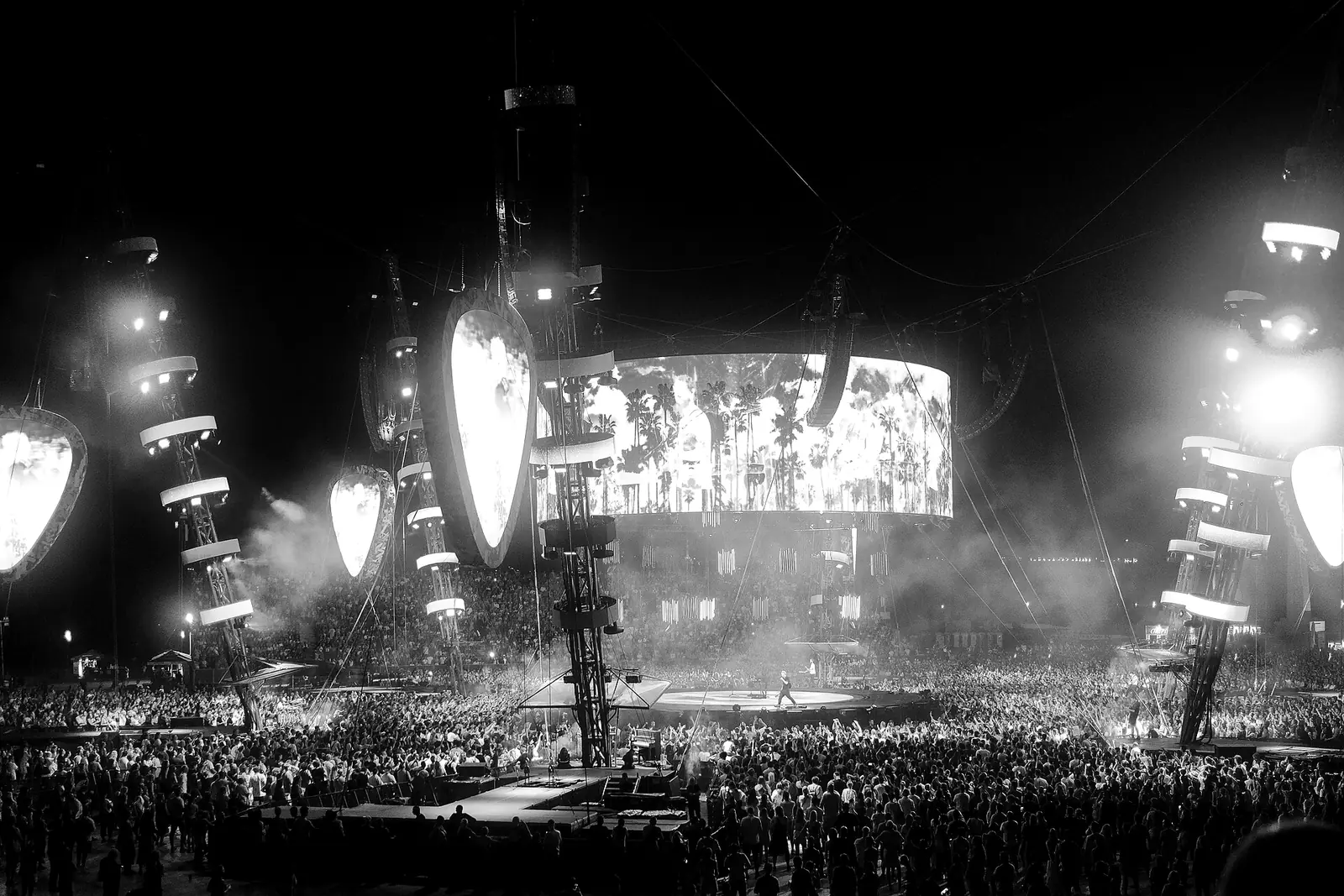 Público de un concierto nocturno frente a un escenario con pantallas y luces